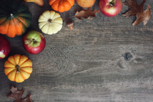 pumpkins and fall leaves on a wood background 