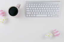 computer keyboard, Easter eggs, and coffee mug on a desk 