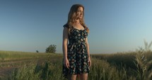 Woman in flower dress outside in summer nature on dirt road.