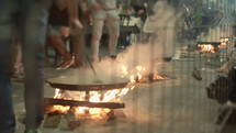 Preparing the traditional Spanish dish of paella over an open fire outdoors, during the Fallas celebration in Valencia, Spain