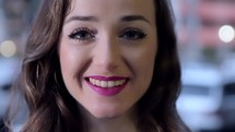 Woman wearing pink lipstick slowly and softly smiling into camera.