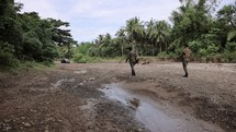 Asian Terrorists Marching Up Dry Riverbed In The Jungle