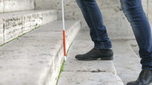 a blind male using a walking stick to walk up steps 