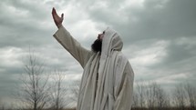 Jesus Christ, bible prophet or religious man lifts his hands toward God in heaven in worship and prayer.
