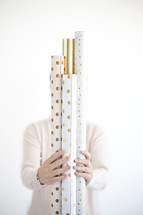 a woman holding rolls of wrapping paper 