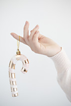 a woman holding a candy cane ornament 