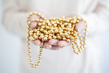 cupped hands with gold beaded garland 
