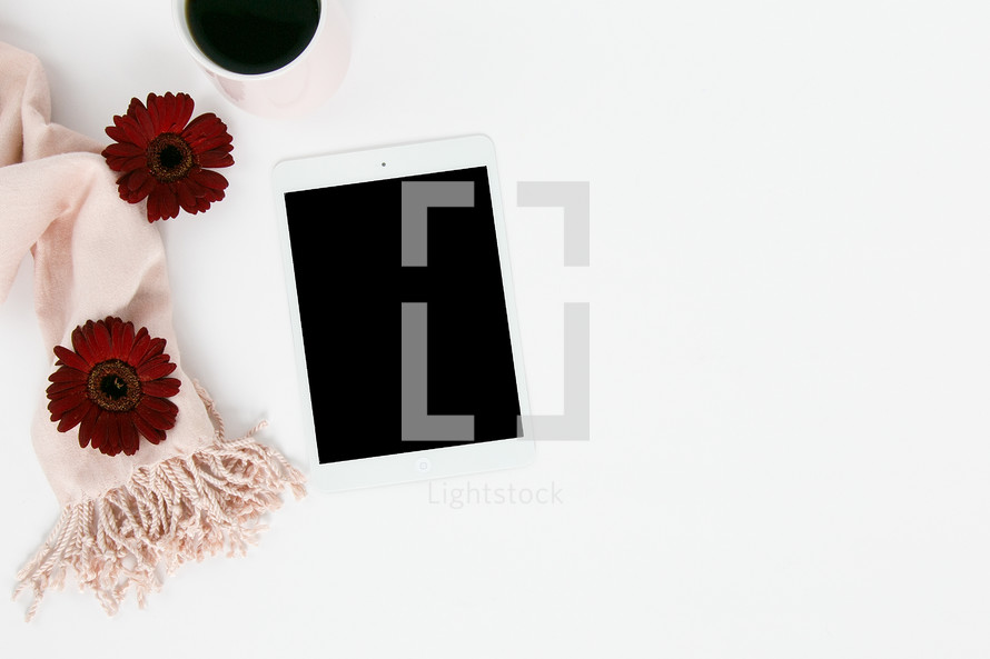 pink scarf, red gerber daisies, iPad, and coffee mug on white background 