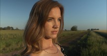 Closeup of face of woman with red hair watching summer sunset.