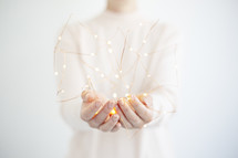 a woman holding fairy lights 