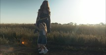 Mother and daughter dancing outside on dirt road in summer sunset.