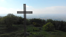 aerial view over green hills and a cross 