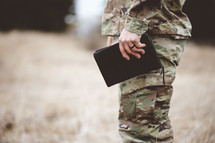 Shallow focus shot of a young soldier holding a bible in a field
