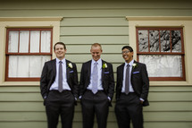 Three groomsmen hangout with hands in their pockets 