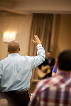 Man in meeting with hands raised
