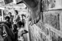 bare feet hanging off of a brick wall 