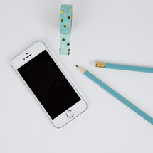iPhone, pencils, and tape on a desk 