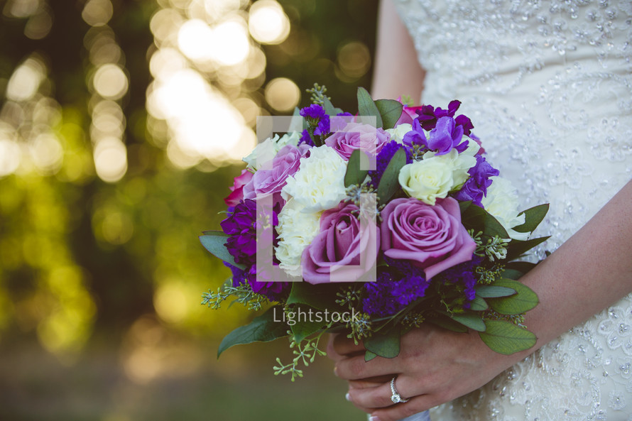 a bride holding a bouquet of purple roses 