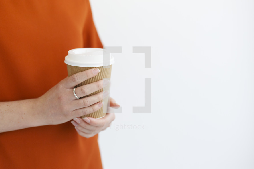 a woman holding a to go coffee cup 
