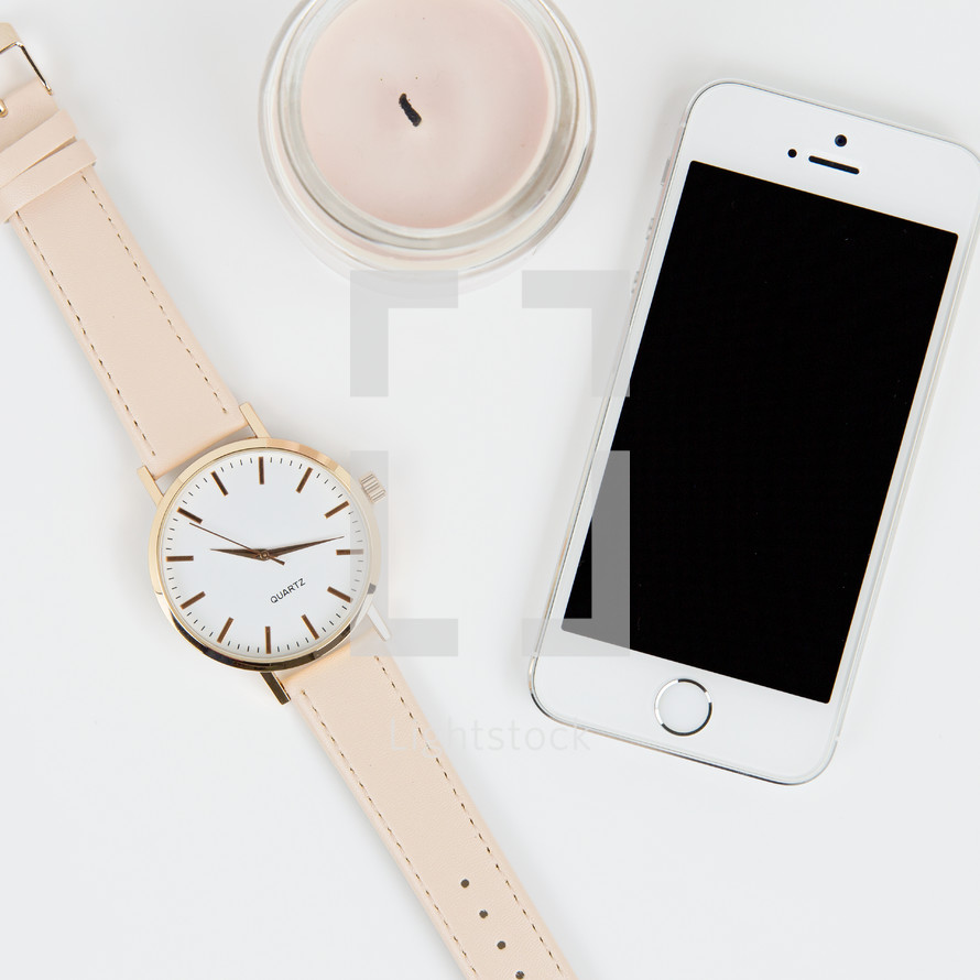 watch, candle, and iPhone on a white background 