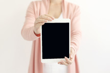a woman holding up a tablet 