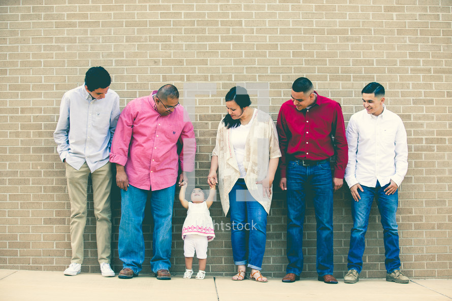 a Latino family standing together in front of a brick wall 