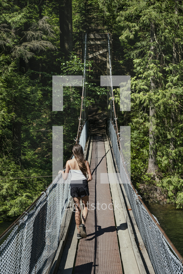 girl walking across a swinging bridge 