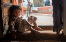 a boy sitting in a doorway in India 