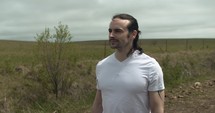 Young man walking on unpaved, dirt road on summer day explore, hiking, worshipping and praying. Lifestyle, worship and prayer concept.