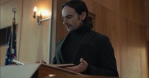 Young pastor in church with bible preaching, teaching sermon to congregation in Sunday morning worship service.