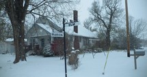 Slow motion Christmas snow scenery. Winter snow storm with buildings, mailbox, and houses covered in snowflakes falling in cinematic slow motion. 