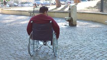 a man in a courtyard at a park in a wheelchair 