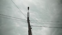 Electrical pole and wires in front of grey, storm, rain clouds.