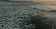 Aerial Drone shot of Surfers Riding Big Waves At Guanacaste Beach In Costa Rica At Sunset.	