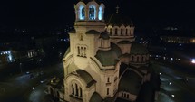 aerial view over a city, church, and bell tower at night 