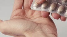 Hand of a Man Who is Taking a Pill Capsule From the Box at Home Dropping Down