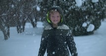 Happy, young boy smiling and playing in snow in cinematic slow motion on Christmas morning. 
