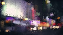 Rain drops falling on window with bokeh lights of city at night. Raining in the city traffic. Rain drops trickle down. 4k