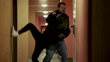 Woman being grabbed and taken by a man in a hallways.