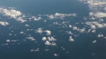 View of planet earth, ocean and clouds from airplane window while flying in cinematic slow motion.