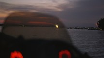 man driving a boat at sunset 