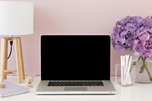 laptop computer on desk and vase of hydrangeas