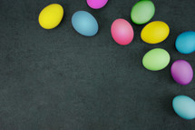 Pastel Easter eggs shot from directly above on black texture background with copy space. 