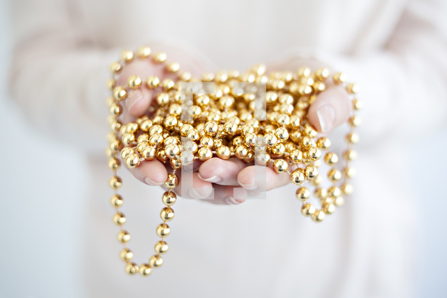 cupped hands with gold beaded garland 