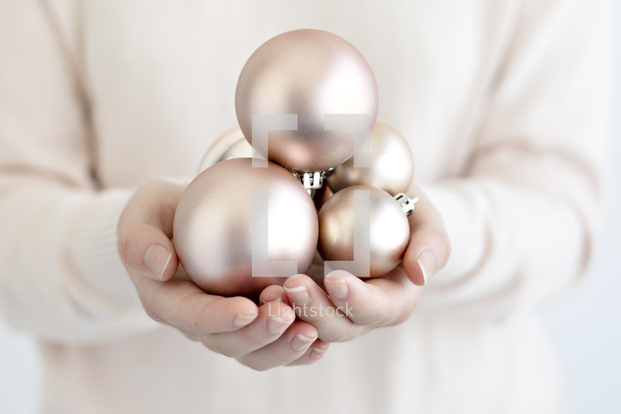 a woman holding Christmas ornaments in cupped hands 