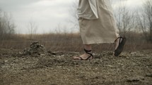 Jesus Christ, bible nomad, Christian prophet, monk or religious man in white tunic and sandals walking in the Jerusalem wilderness in cinematic slow motion.
