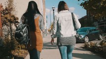 friends walking down a sidewalk talking 