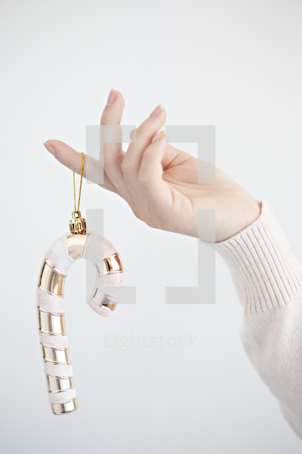 a woman holding a candy cane ornament 