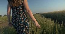 Woman in flower dress touching grass walking in slow motion.