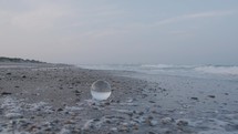 Sea waves washing the shore with glass orb